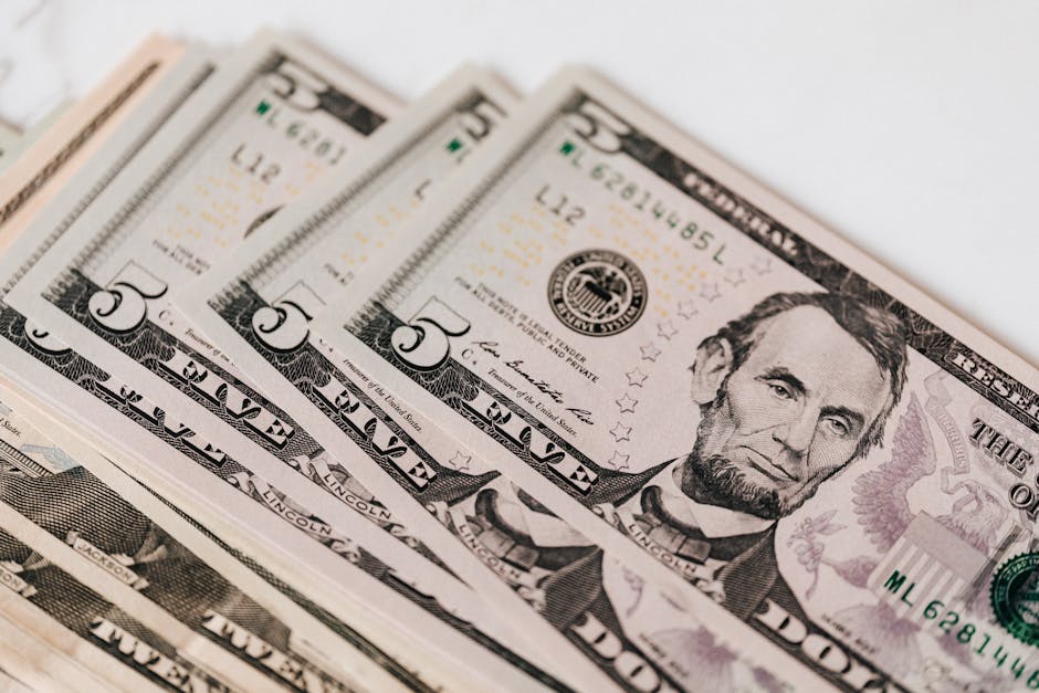 High-quality image of five dollar bills in a neat stack, representing currency and financial concepts.